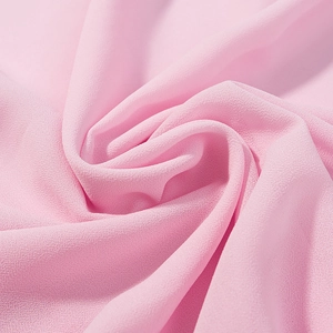 Macro detail of light pink chiffon fabric showing texture and soft spiral pleats
