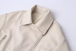 Detail of off-white faux leather biker jacket featuring lapels and silver zipper hardware