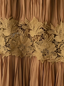 Detail of brown pleated fabric with delicate floral embroidery lace on a summer dress