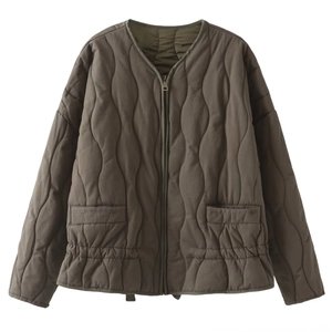 Detail of olive quilted jacket featuring a metallic zipper and elasticated waist hem