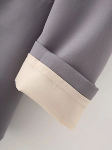 Detailed close-up of grey blazer sleeve with neat stitching and beige lining contrast