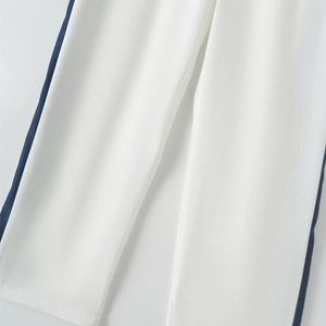 Close-up of white trousers with a wide navy blue side stripe and high-quality hem stitching