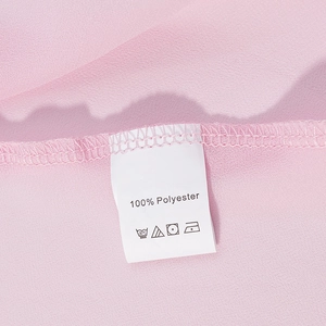 Detail view of pink polyester fabric and care instruction label showing 100% polyester