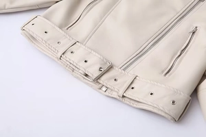 Detail of cream PU biker jacket hem with silver buckle belt and textured faux leather