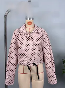 Detail of pink puff sleeve jacket with black polka dots featuring stand collar and drawstring