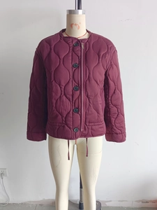 Detail of burgundy quilted jacket showing wave pattern, crew neck and button closure