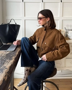 Detail of a dark brown suede jacket featuring a stand collar and large flap pockets