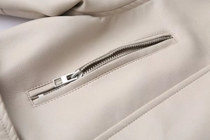 Detailed close-up of the silver metal zipper and textured faux leather on the beige jacket