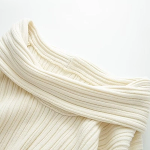 Detailed close-up of ribbed knit texture on an off-white off-shoulder sweater