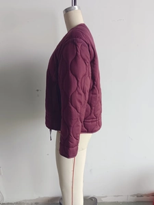 Detail of maroon quilted jacket featuring elegant wavy stitching and stand collar