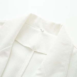 Close-up of white waffle weave texture on loose-fit coat collar with detailed fabric view
