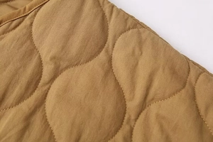 Detailed close-up of khaki quilted cotton jacket with gourd stitching pattern and texture