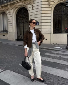 Close-up of a brown suede jacket with white shirt and beige pants in European street style