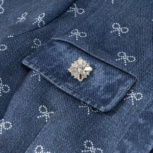 Detail of blue denim fabric with bow prints and a radiant rhinestone buckle on the pocket