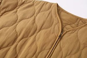 Macro detail of camel quilted jacket showing fine onion stitching and metal zipper