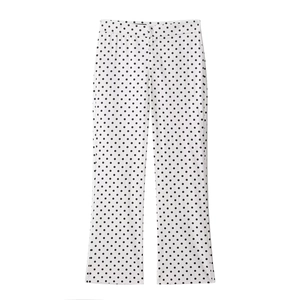 Detailed view of high-waist white trousers with black polka dots and smooth fabric