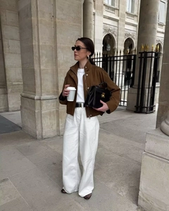 Street style shot of a woman in a brown suede utility jacket and white wide-leg trousers
