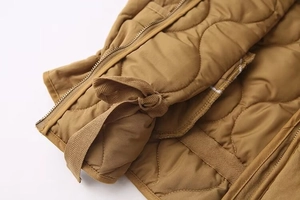 Detail of camel quilted jacket showing gourd stitching and metal zipper closure