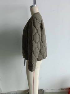 Side view of olive green quilted jacket featuring a drawstring hem and gourd stitching
