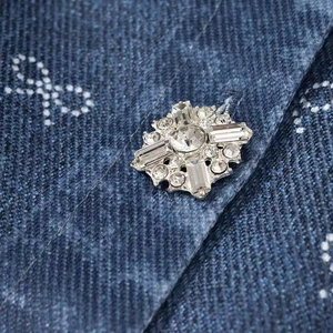 Close-up of sparkling rhinestone bow detail on dark blue polka dot denim dress fabric
