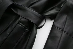 Detail of black faux leather jacket showing pocket stitching and waist belt loops
