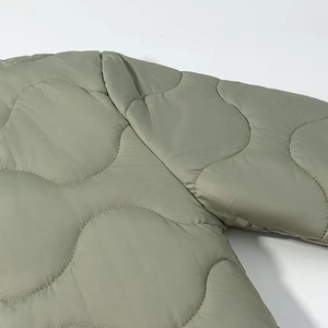 Detail of light olive green quilted jacket featuring classic onion stitch pattern