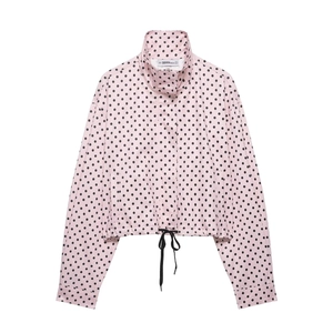 Detail of pink polka dot bomber jacket featuring high stand collar and black drawstring hem