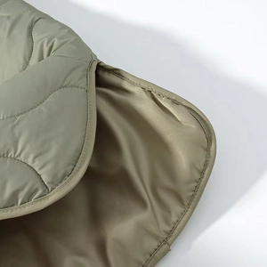 Detail view of olive green quilted jacket featuring wave stitching and smooth lining
