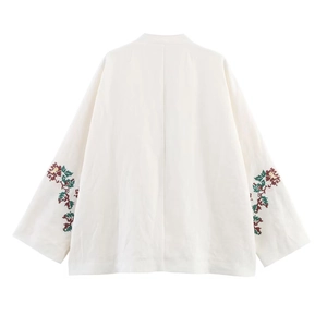 Detail of floral embroidery on the sleeve of a white linen kimono cardigan jacket