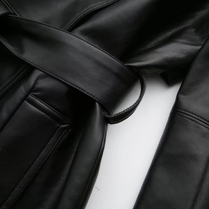Close-up of black faux leather jacket featuring waist belt, loops and stitched side pocket