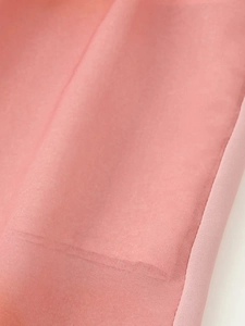 Détail de l'ourlet en tissu tie-dye rose avec coutures délicates et texture légère