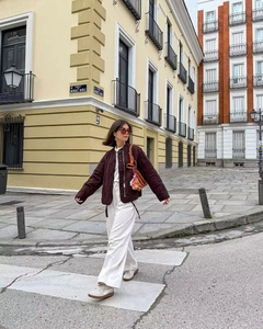 Close-up of deep brown quilted jacket with drawstring detail and white wide-leg trousers