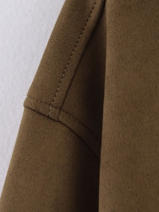 Detailed macro view of the double stitching on high-quality tan suede jacket fabric