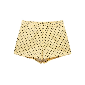 Detailed view of yellow high-waisted shorts with black polka dots and belt loops