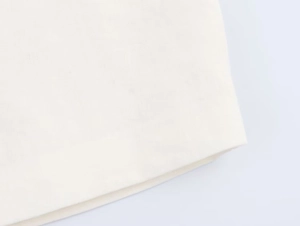 Close-up of beige linen fabric texture and clean stitched hem on the kimono shirt