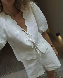 Detailed view of white linen set featuring scalloped edges and tie-front puff sleeve top