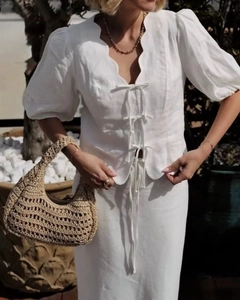 Close-up of white cotton set featuring scalloped edges and delicate tie-front ribbons