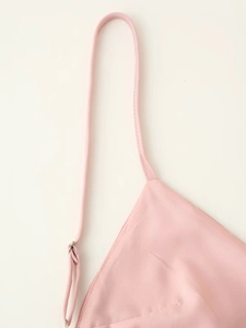 Détail de la fine bretelle réglable sur une robe en satin rose avec boucle argent