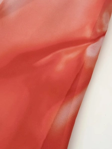 Gros plan du tissu dégradé orange-rouge avec texture tie-dye délicate et finition légère