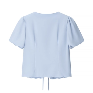 Detail of light blue short sleeve top featuring back tie and scalloped wave hemline