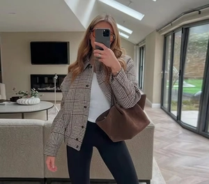 Detail of a brown plaid bomber jacket for women paired with a chic tote bag and casual outfit