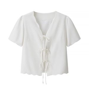 Detailed view of scalloped edges and tie-front bow design on a white short sleeve top