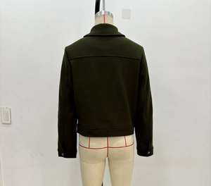 Detail of the back view of a dark green short wool jacket with a seam and metal cuffs