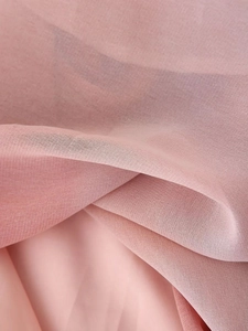 Gros plan sur un tissu mousseline rose semi-transparent avec texture mesh et drapé doux