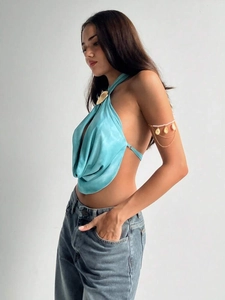 Detail of teal satin halter top featuring metallic shell buckle and elegant draped neckline