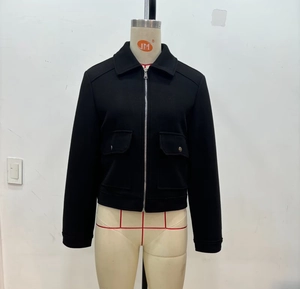 Detail of a black cropped tweed jacket with large flap pockets and silver zipper closure