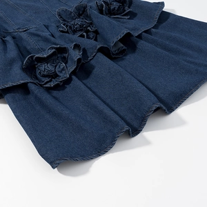Detail of dark blue denim dress featuring 3D floral appliques and ruffled layers