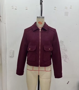 Detail of wine red tweed jacket with gold zipper and dual flap pockets on mannequin