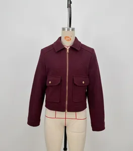 Detail of wine red tweed jacket with gold zipper and dual flap pockets on mannequin