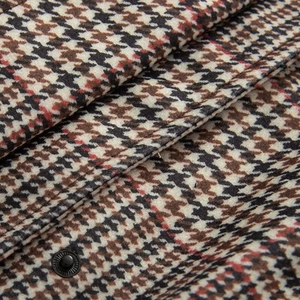 Macro shot of houndstooth wool blend fabric with a high-quality black metal snap button